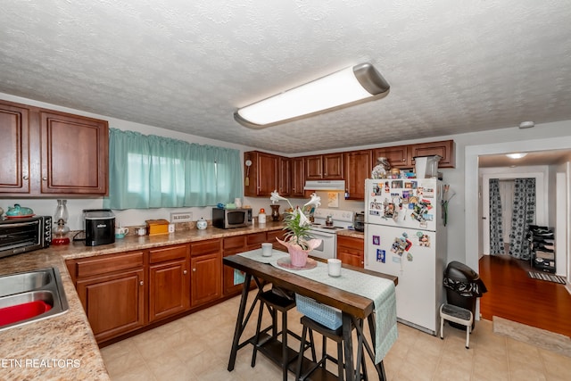 kitchen with white appliances, a textured ceiling, sink, light wood-type flooring, and a breakfast bar