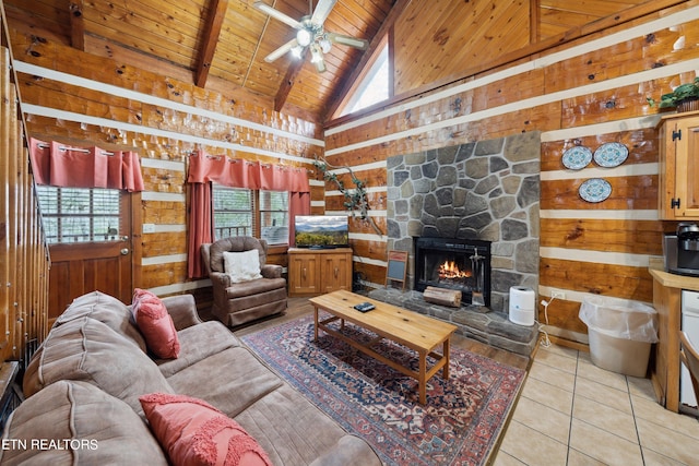 tiled living room featuring ceiling fan, a stone fireplace, high vaulted ceiling, wood ceiling, and wooden walls