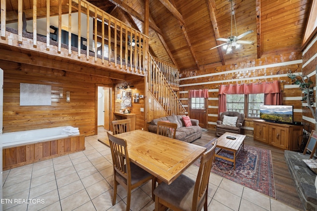 tiled dining room featuring high vaulted ceiling, ceiling fan, beamed ceiling, wooden walls, and wood ceiling