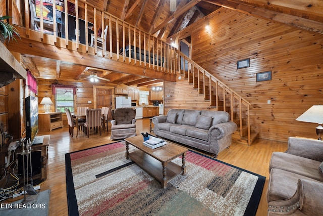 living room with wooden walls, wood ceiling, high vaulted ceiling, and light wood-type flooring