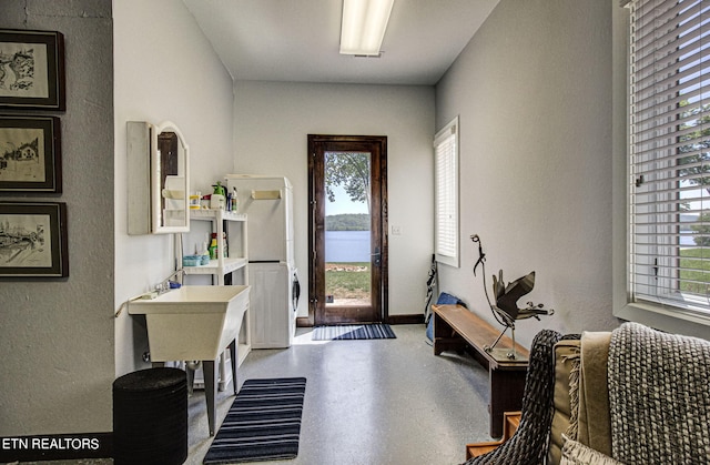 foyer entrance with stacked washing maching and dryer, a water view, and a healthy amount of sunlight