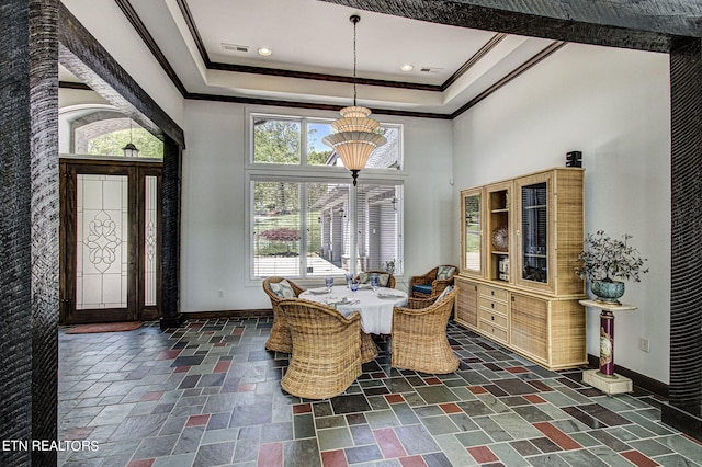 dining space featuring a tray ceiling, crown molding, and a towering ceiling