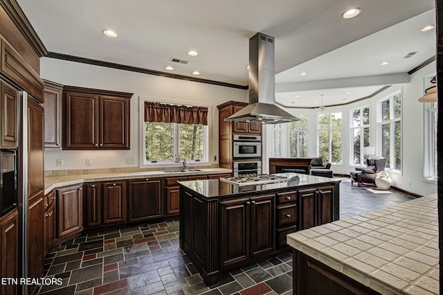 kitchen featuring sink, ceiling fan, a kitchen island, dark brown cabinetry, and island exhaust hood