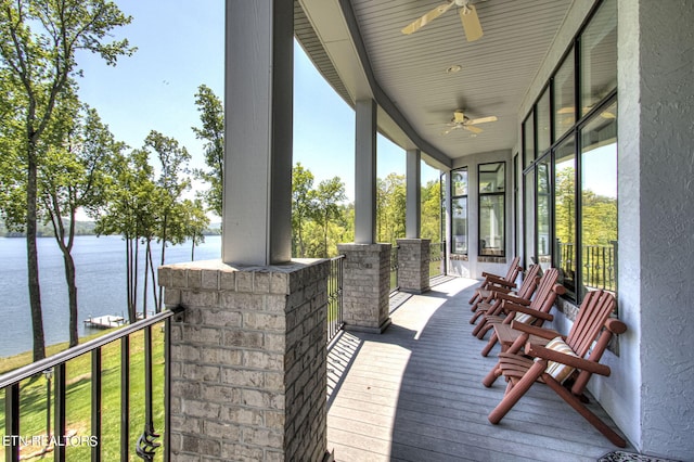 wooden deck with a lawn, ceiling fan, and a water view