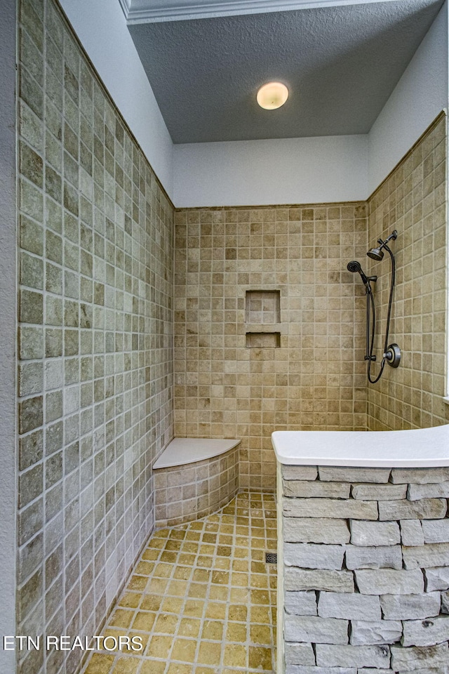 bathroom with tile patterned floors, a tile shower, and a textured ceiling