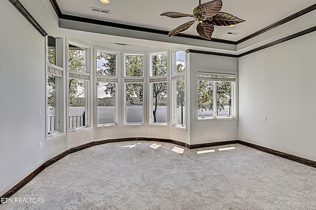 spare room with carpet flooring, crown molding, a tray ceiling, and ceiling fan