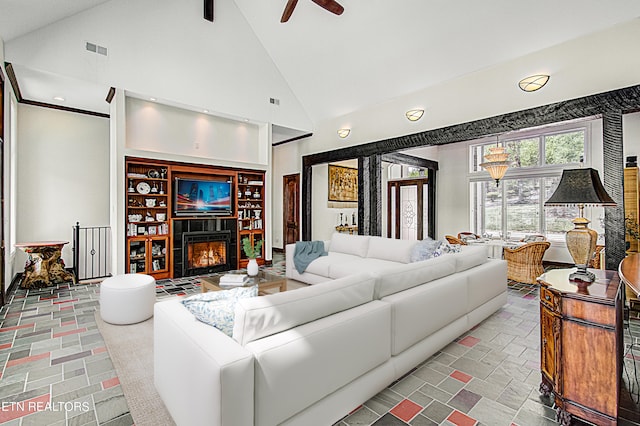 living room with high vaulted ceiling, ceiling fan, and a tiled fireplace