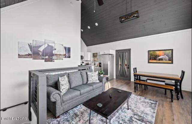 living room featuring ceiling fan, a high ceiling, and wood-type flooring