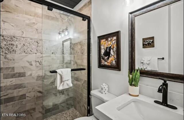 bathroom with toilet, an enclosed shower, and sink