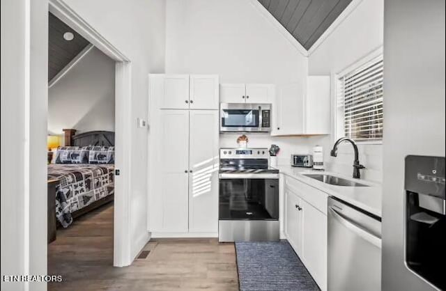 kitchen featuring white cabinets, appliances with stainless steel finishes, sink, and light wood-type flooring