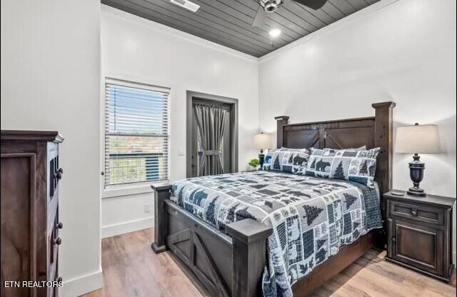 bedroom featuring crown molding, light hardwood / wood-style floors, wood ceiling, and ceiling fan