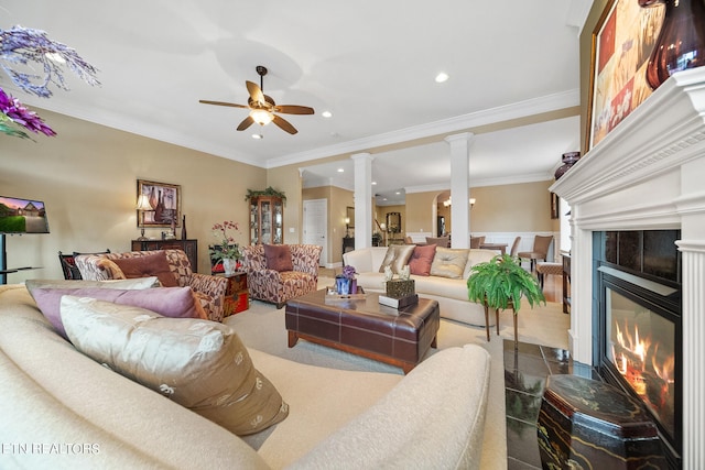 living room featuring ornamental molding, ceiling fan, decorative columns, and a tile fireplace