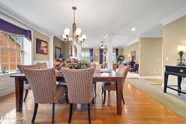 dining space featuring ceiling fan with notable chandelier, light hardwood / wood-style flooring, ornate columns, and ornamental molding