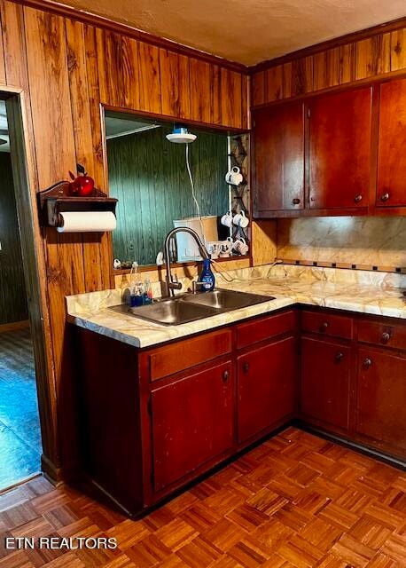 kitchen with wooden walls, sink, and parquet floors