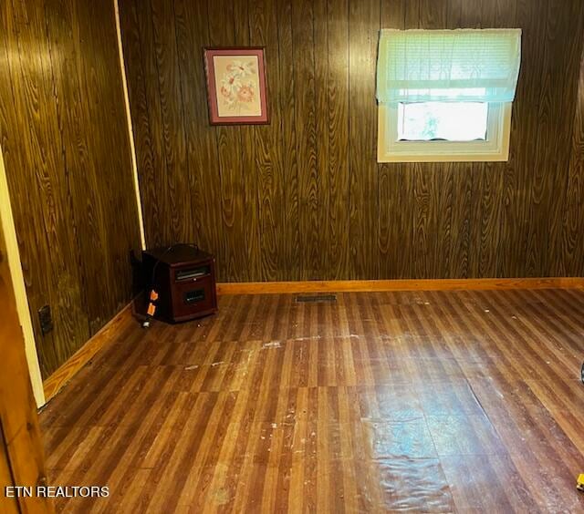 unfurnished room featuring wood-type flooring and wooden walls