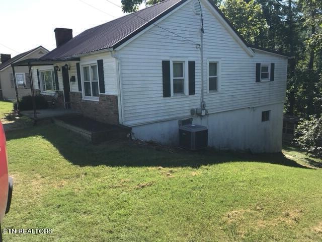 back of house with central AC and a yard