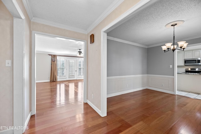 unfurnished dining area with crown molding, a textured ceiling, and light hardwood / wood-style flooring