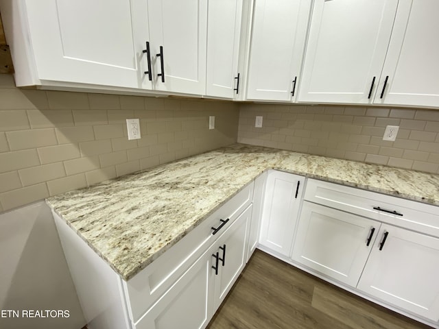 interior space featuring light stone counters, white cabinetry, dark hardwood / wood-style floors, and decorative backsplash