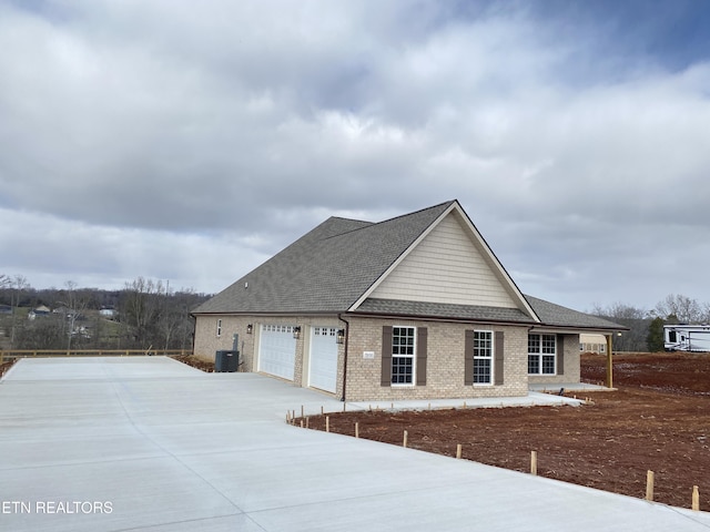 view of front of house featuring brick siding, a shingled roof, central air condition unit, concrete driveway, and an attached garage