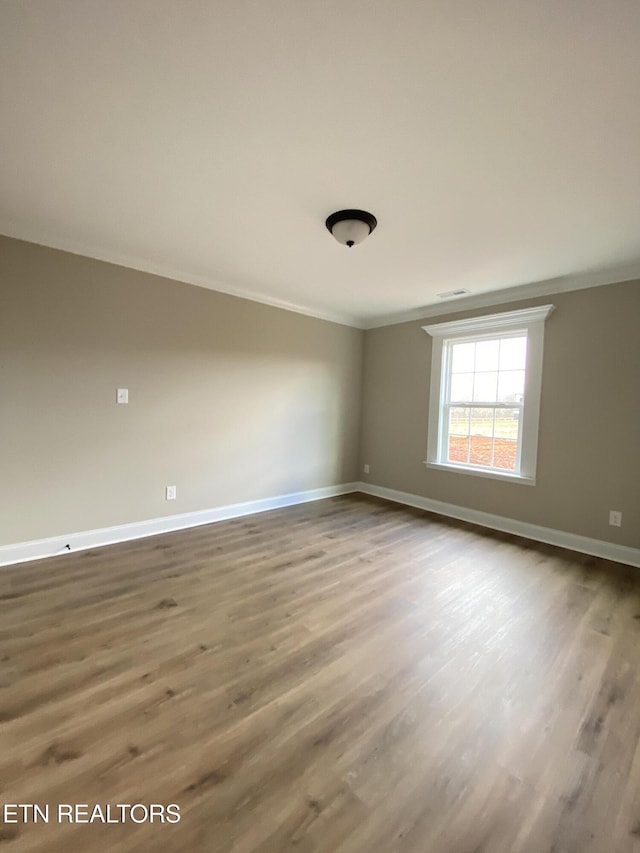 unfurnished room featuring wood-type flooring and crown molding