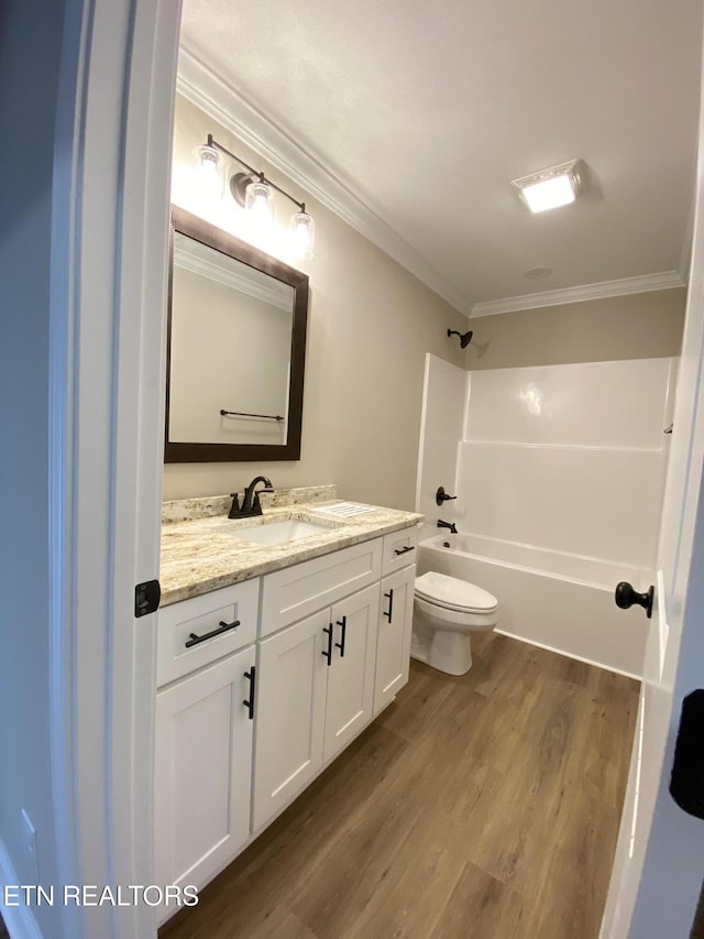 full bathroom featuring washtub / shower combination, toilet, wood-type flooring, crown molding, and vanity