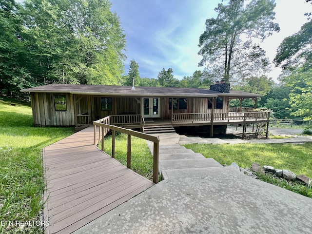 view of front of house featuring a wooden deck, french doors, and a front yard