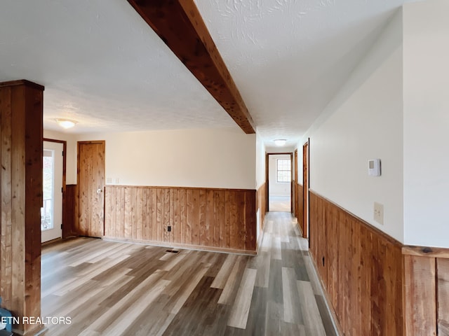 corridor featuring wooden walls, a textured ceiling, and hardwood / wood-style flooring