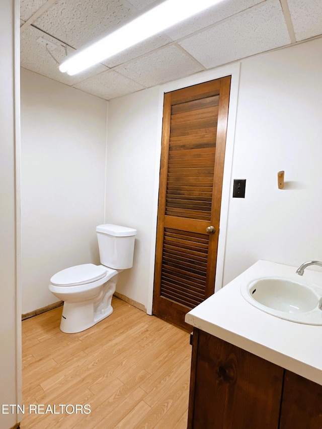 bathroom with a paneled ceiling, vanity, toilet, and wood-type flooring