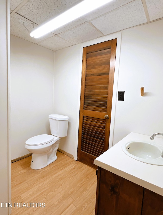 bathroom featuring a paneled ceiling, hardwood / wood-style floors, vanity, and toilet