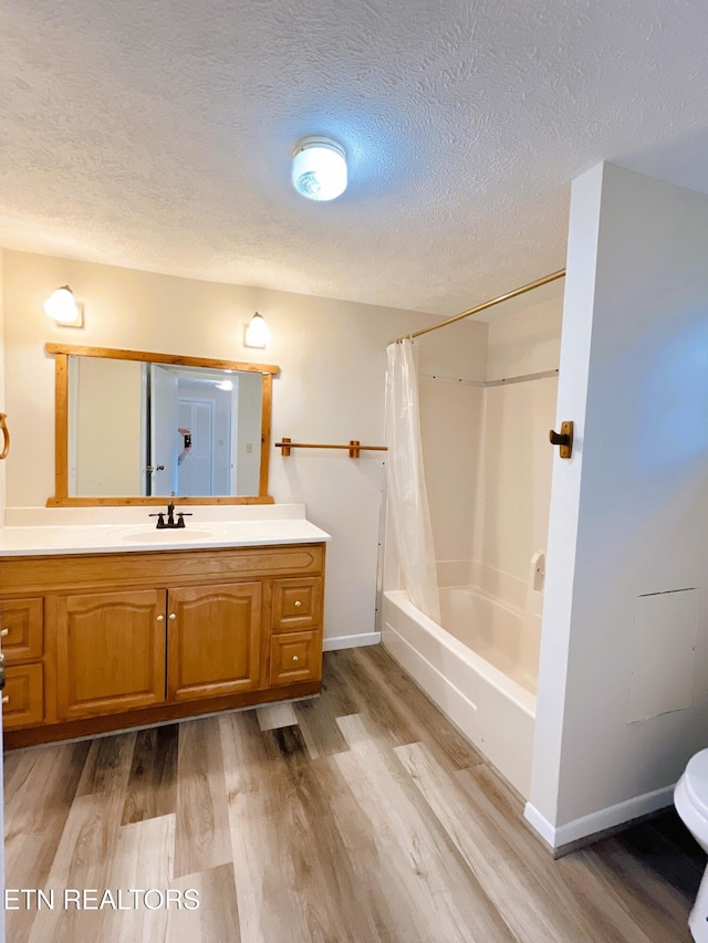 full bathroom featuring shower / bath combination with curtain, a textured ceiling, toilet, vanity, and hardwood / wood-style flooring