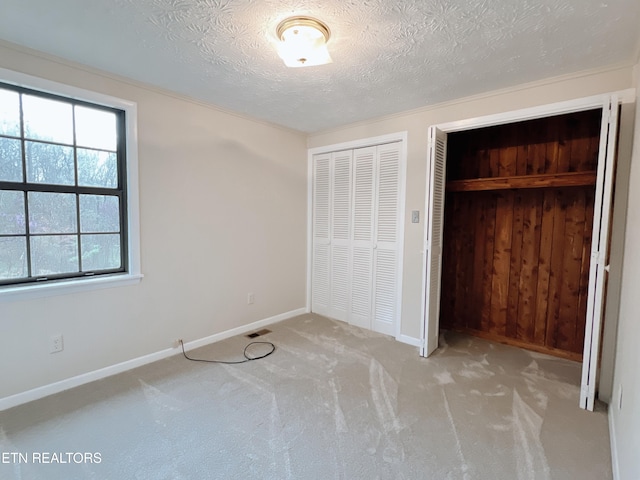 unfurnished bedroom with light colored carpet, a textured ceiling, and two closets