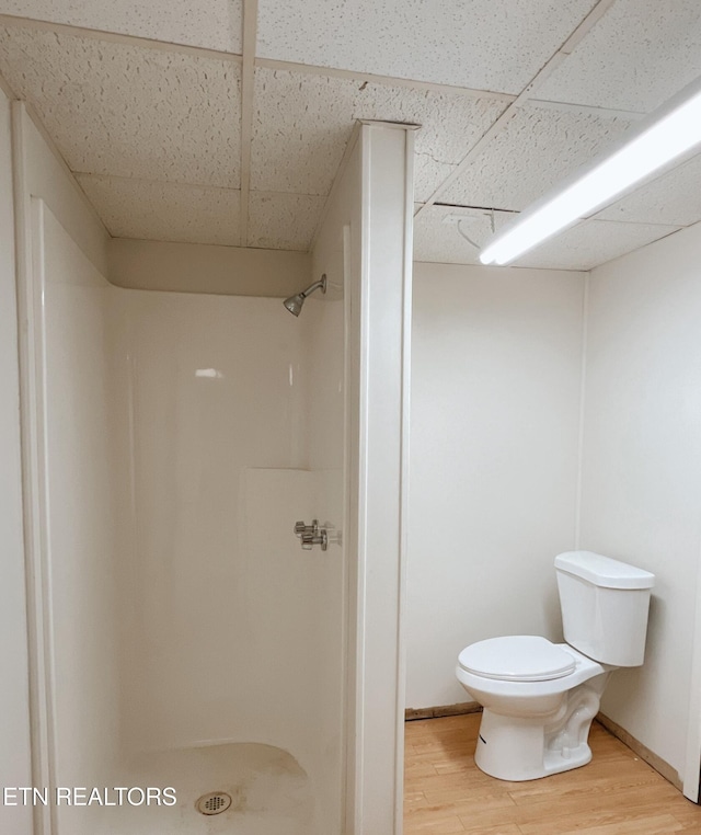 bathroom featuring a paneled ceiling, a shower, toilet, and hardwood / wood-style flooring