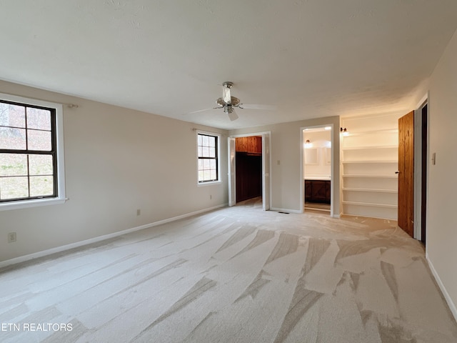 unfurnished bedroom featuring a walk in closet, ensuite bath, ceiling fan, light colored carpet, and a closet