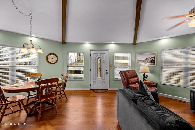 dining area with ceiling fan with notable chandelier, dark hardwood / wood-style floors, and vaulted ceiling with beams