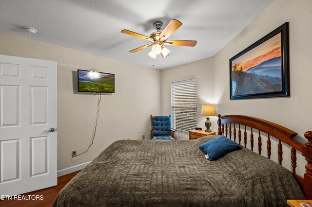 bedroom with dark hardwood / wood-style flooring, ceiling fan, and a textured ceiling