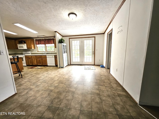 kitchen featuring a textured ceiling, white appliances, crown molding, and light tile floors