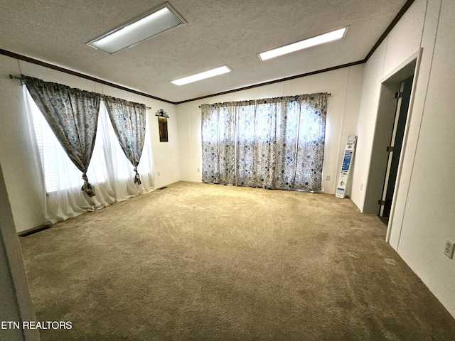 carpeted empty room featuring ornamental molding, a wealth of natural light, and a textured ceiling