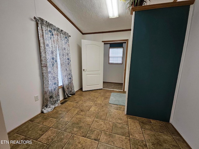 empty room with a textured ceiling, crown molding, and dark tile floors