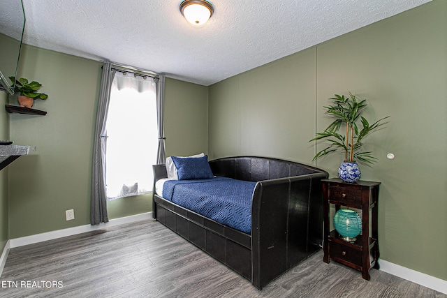 bedroom featuring a textured ceiling, hardwood / wood-style floors, and multiple windows