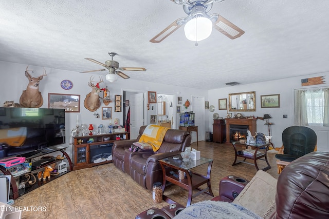 living room featuring ceiling fan, hardwood / wood-style flooring, and a textured ceiling