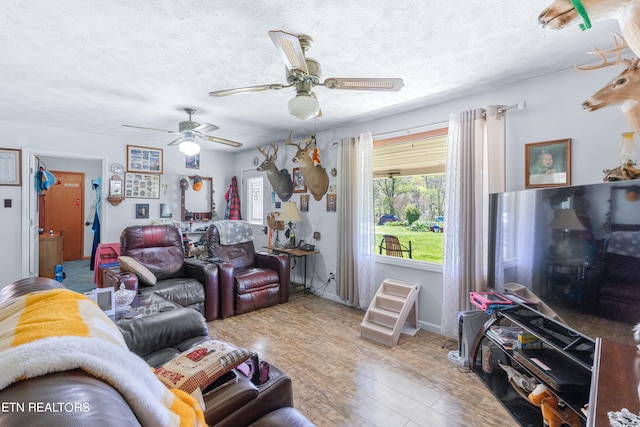 living room with light hardwood / wood-style flooring, ceiling fan, and a textured ceiling