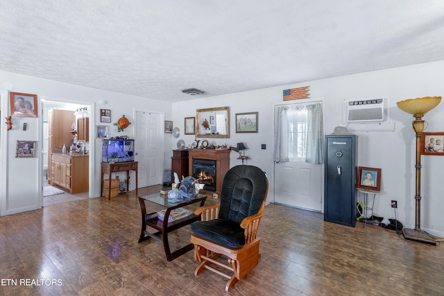 living room with a textured ceiling, dark wood-type flooring, and a wall mounted AC