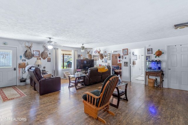 living room with dark hardwood / wood-style floors, ceiling fan, and a textured ceiling