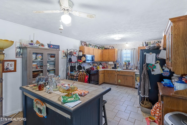 kitchen featuring ceiling fan, light tile floors, a textured ceiling, stainless steel appliances, and tile counters