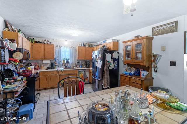 kitchen with tile counters, light tile floors, stainless steel appliances, and a textured ceiling