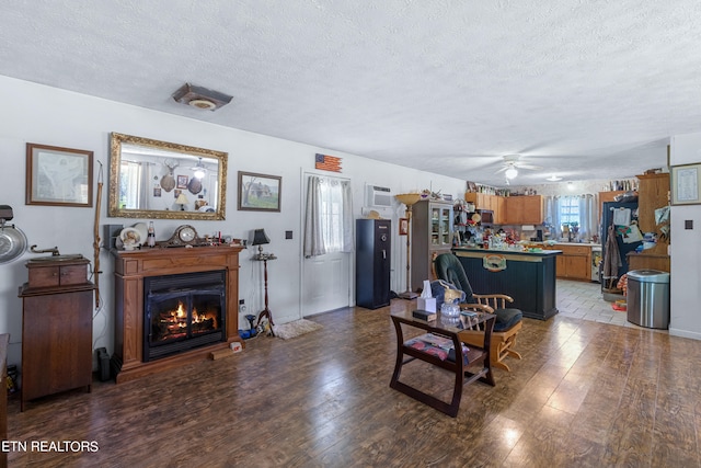 living room featuring plenty of natural light, dark wood-type flooring, ceiling fan, and a textured ceiling