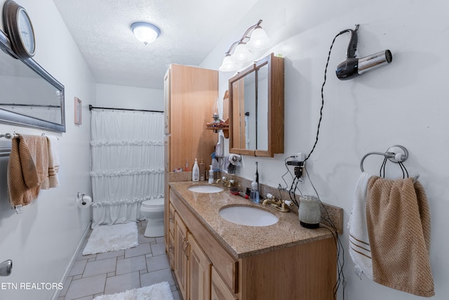 bathroom featuring dual vanity, toilet, a textured ceiling, and tile flooring