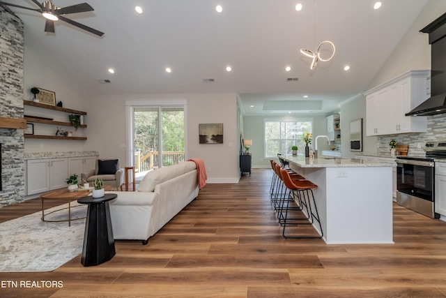 kitchen with white cabinetry, a breakfast bar, an island with sink, and electric stove