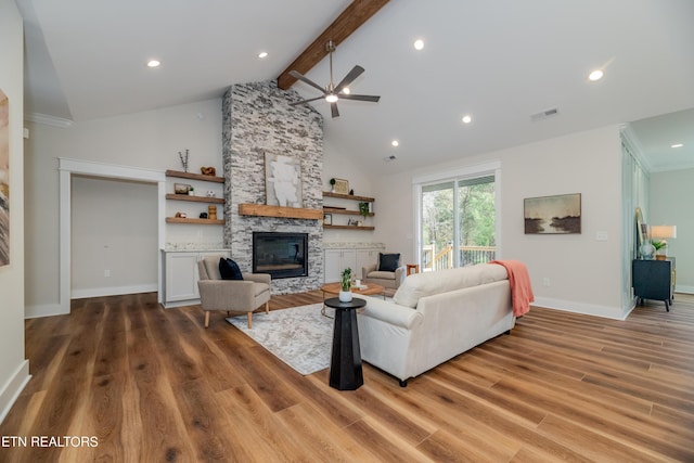 living room featuring a stone fireplace, high vaulted ceiling, hardwood / wood-style flooring, ceiling fan, and beam ceiling