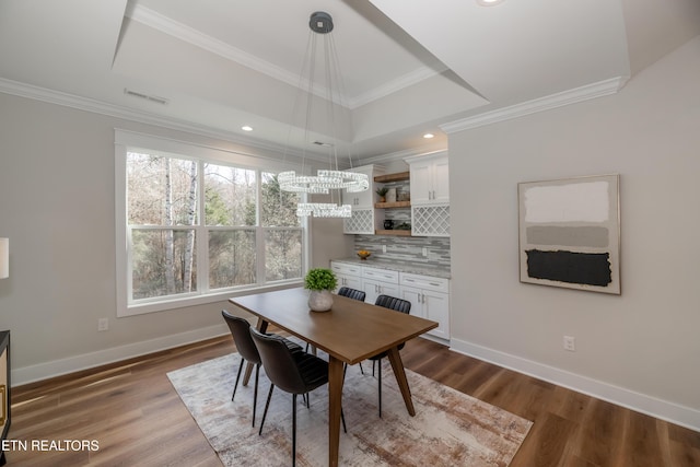 dining room featuring a tray ceiling, ornamental molding, and dark hardwood / wood-style floors